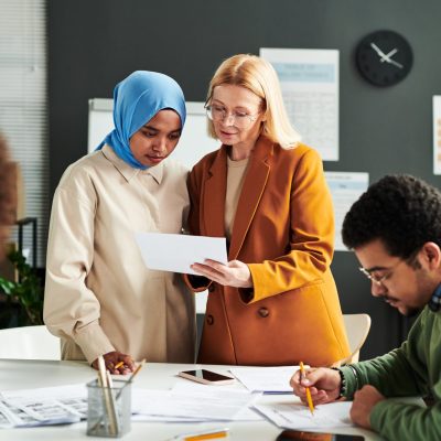 Professeur blonde mature montrant un document avec un test à une étudiante musulmane
